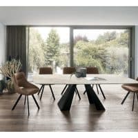 Elegante tavolo in gres Taurus di Alpe Arredi, ideale per ambienti moderni e raffinati, con sedie in stile contemporaneo e grande finestra che offre vista sul giardino.