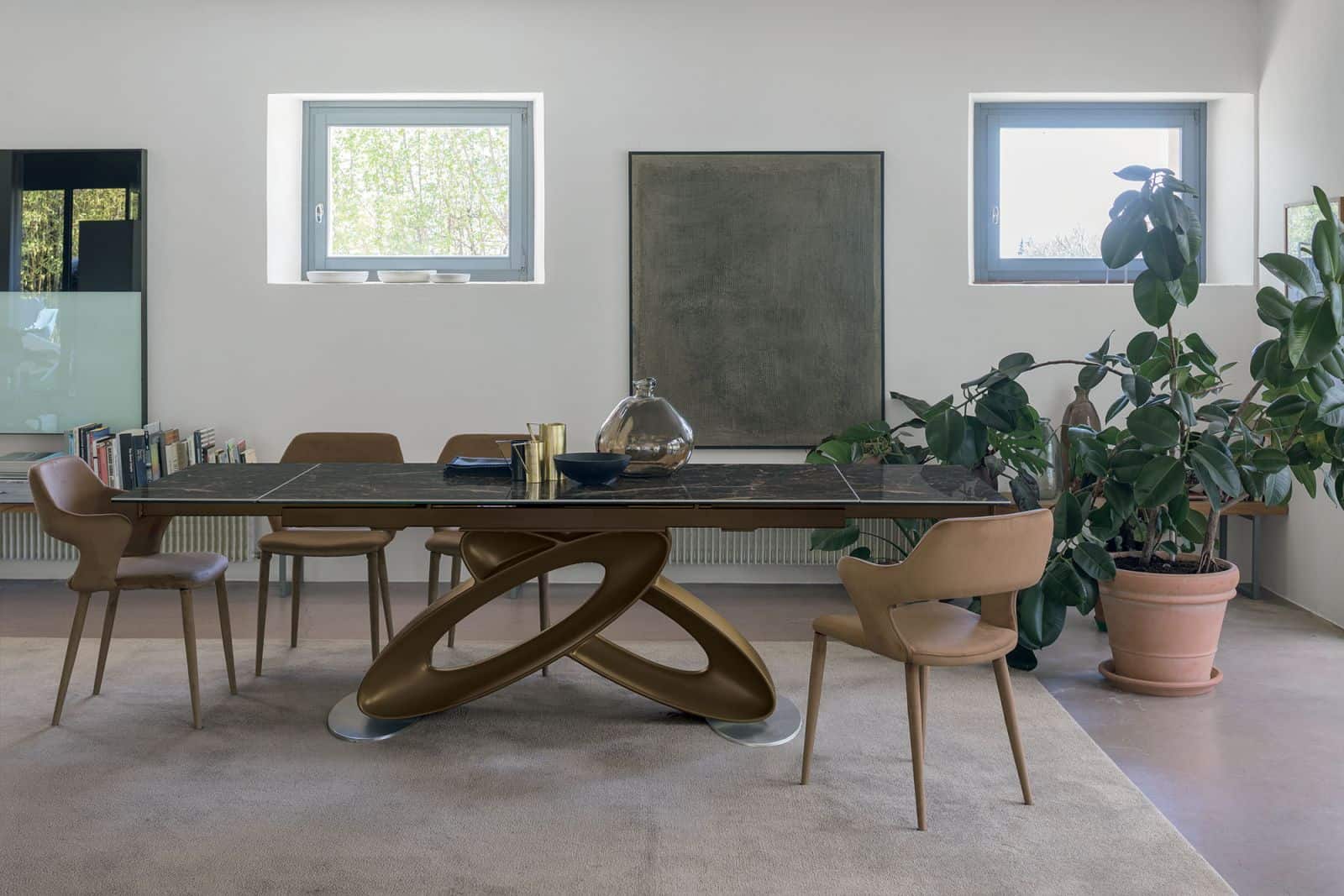 LALT: Tavolo da pranzo moderno in legno e marmo con sedie di design in ambiente luminoso e minimalista, decorato con piante e opere d'arte.