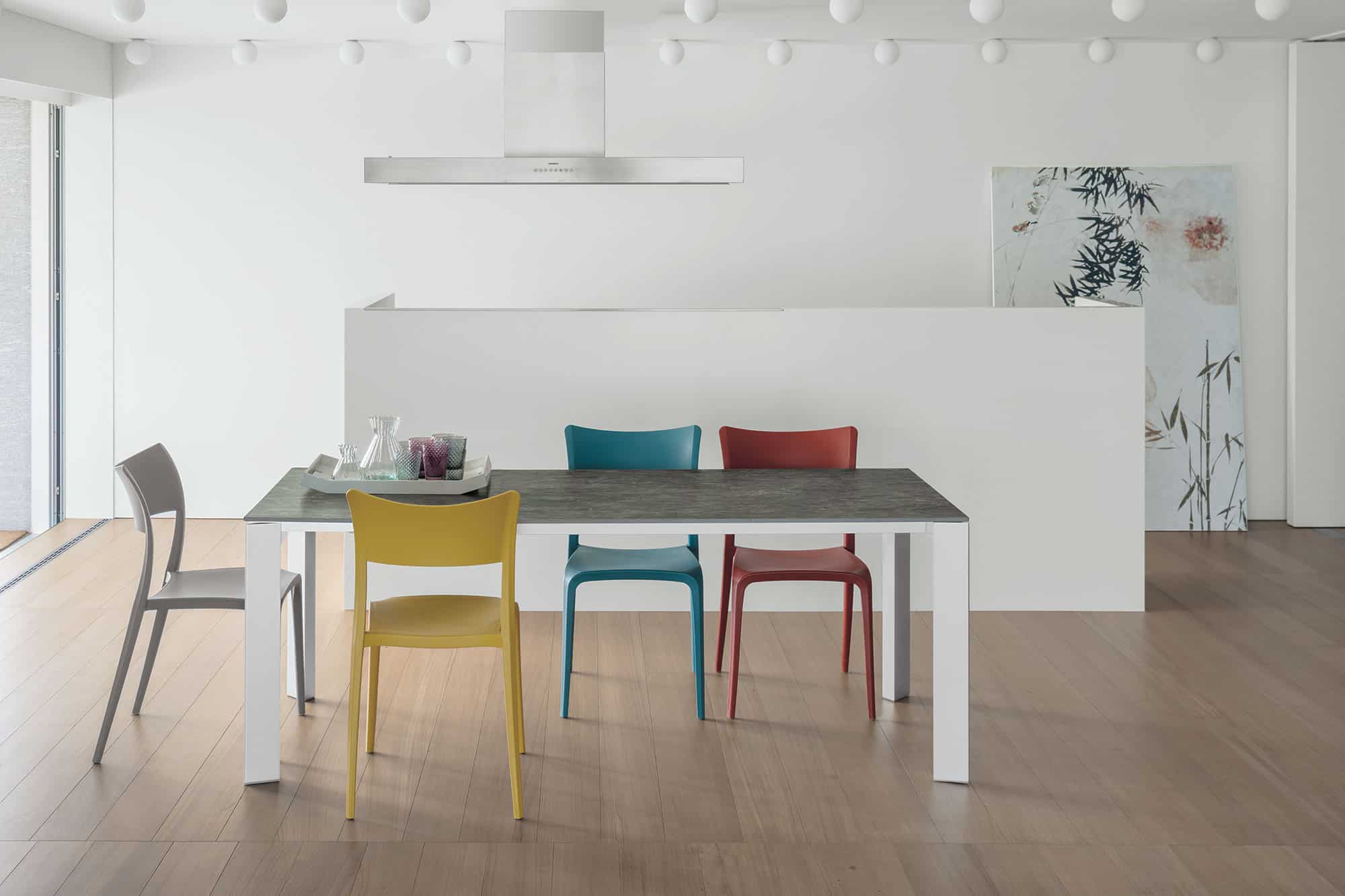 Colorful modern chairs around a dining table in a minimalist kitchen.