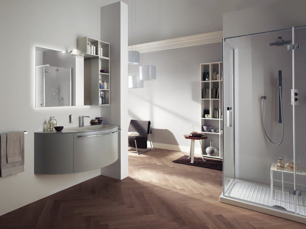 aquo_pag_212_213 Elegante bagno moderno con specchio illuminato, arredi funzionali, cabina doccia walk-in e scaffali minimalisti, in ambientazione contemporanea, perfetta per arredi di alta qualità.
