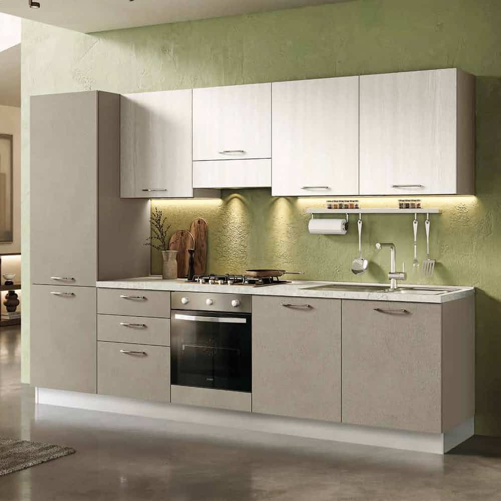 Cucina moderna con ante bianche e piano in laminato chiaro, illuminata da luci sottopensile, con accessori da cucina e lavello integrato.