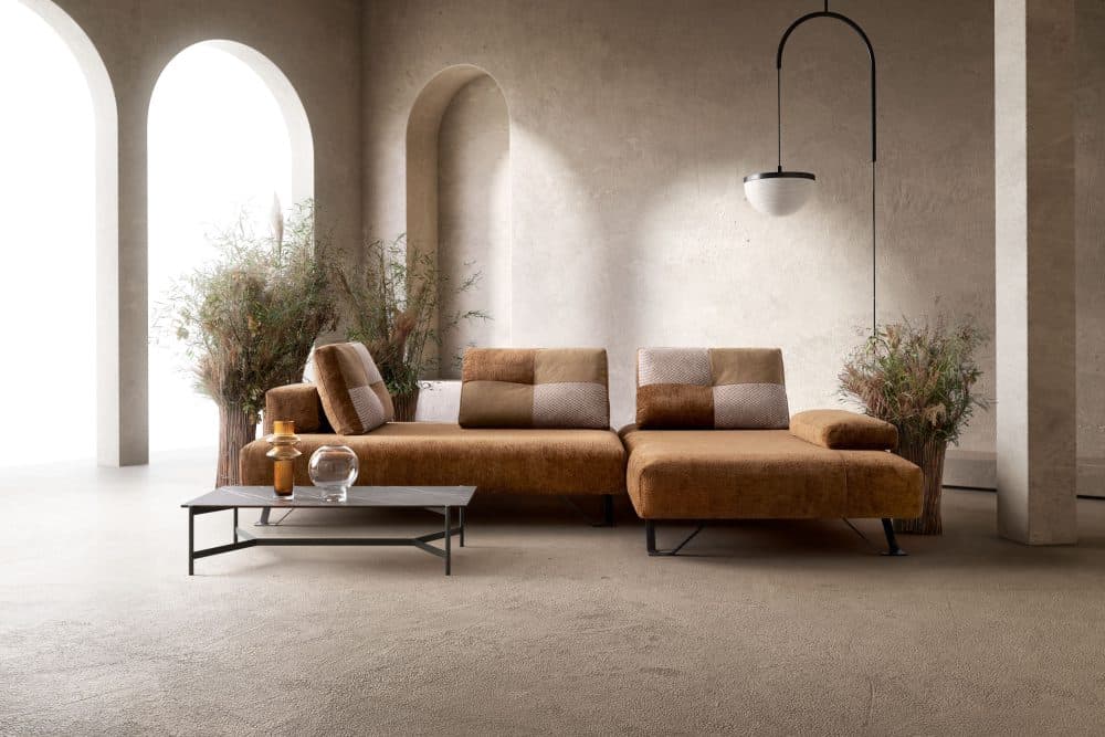 Elegante divano in tessuto marrone con cuscini abbinati, ideale per spazi living moderni e di design, perfetto per apprezzare lo stile e la qualità di Alpe Arredi.
