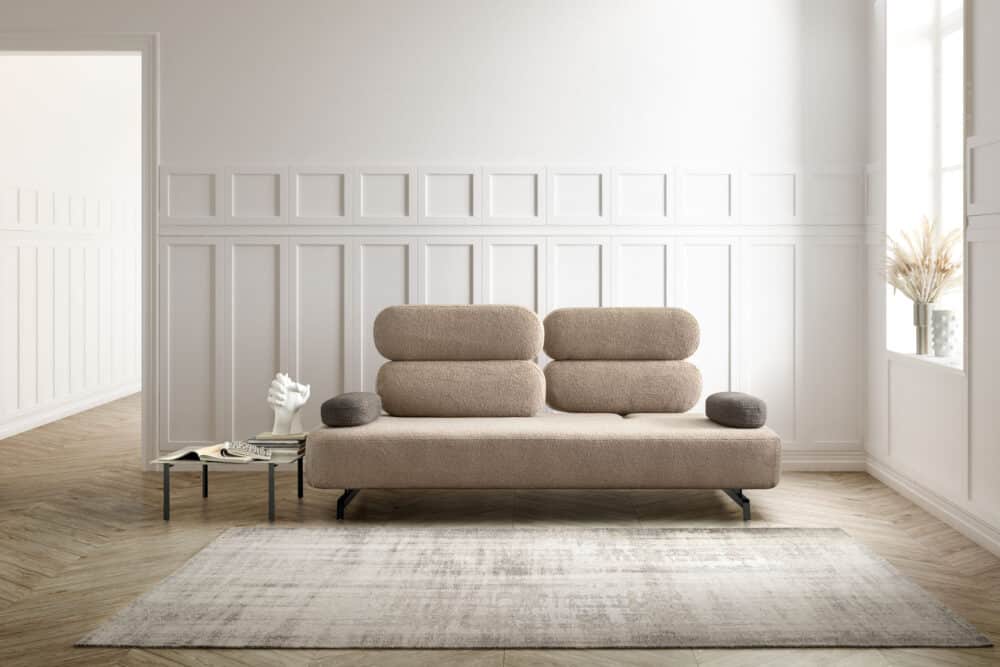 divano-avalon-collezione-divine-3-1000x667 Divano moderno in tessuto beige in un soggiorno minimalista con pareti bianche e pavimento in legno chiaro, arredamento elegante e luce naturale, spazio ideale per living di design.