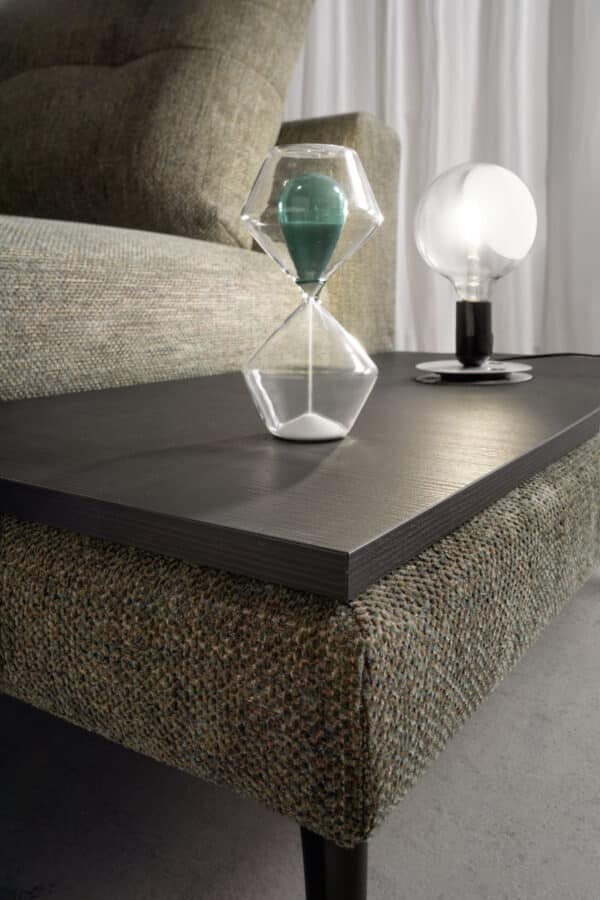 divano-dafne-collezione-experience-4-600x900 Elegante tavolino in legno nero con oggetti decorativi in vetro e luce soffusa, perfetto per soggiorno moderno.