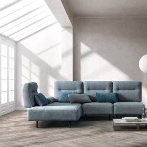Divano moderno in tessuto grigio in un soggiorno luminoso con grande finestra e luce naturale, arredi eleganti e atmosfera accogliente, perfetto per arredare la casa con stile.