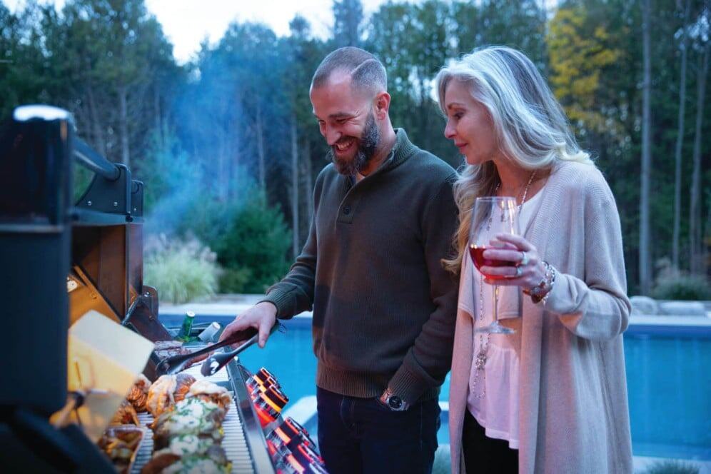 PRO825RSBIPSS-3-Web-Gallery-05-Prestige-Pro825-3-Life-Man-and-Woman-Grilling-Dusk Deliziosi piatti alla griglia con amici in un ambiente naturale e rilassante, perfetto per cene all'aperto in un residence di charme come Alpe Arredi. Semplicità, convivialità e natura si incontrano in questa esperienza culinaria.