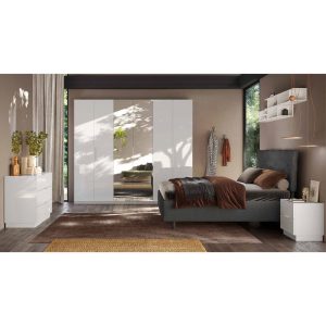 Armadio a muro bianco lucido con specchio, letto matrimoniale con testiera grigia e biancheria morbidamente colorata, mobile porta-parete e decorazioni moderne, ambiente dallo stile contemporaneo.