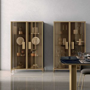 Vetrina moderna in vetro e metallo per arredi di alta qualità, ideale per salotti e soggiorni eleganti, con disposizione di accessori decorativi e stoviglie.