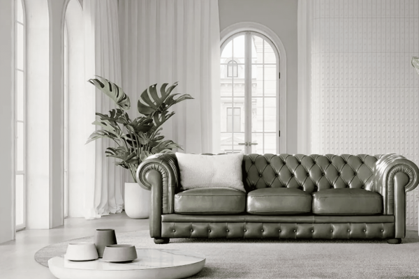 Elegante divano Chesterfield in pelle verde oliva in un soggiorno luminoso, decorato con piante verdi e complementi moderni, è perfetto per arredamenti di alta qualità e stile sofisticato.