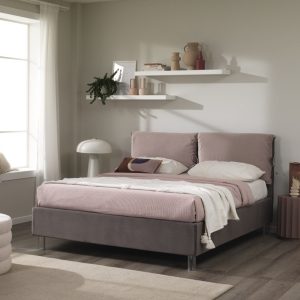 Letto matrimoniale con testiera imbottita in tessuto rosa chiaro, in una camera moderna con pareti bianche e decorazioni minimaliste.