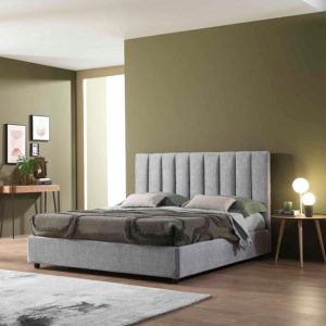 Letto matrimoniale con testiera imbottita grigia in una camera moderna con pareti verde oliva e pavimento in legno.