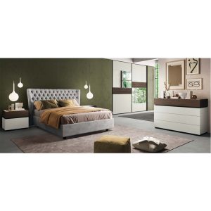 Camera da letto moderna con parete verde, letto imbottito, armadio a specchio e comò con decorazioni minimaliste, ambientazione elegante e luminosa.