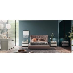 Camera da letto moderna con parete blu, letto imbottito e mobili bianchi, decorata con piante e lampade, ambiente elegante e accogliente.