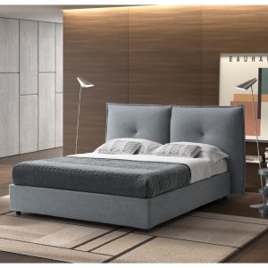Letto matrimoniale moderno con testiera imbottita in tessuto grigio in camera elegante con pareti in legno e decorazioni minimaliste.