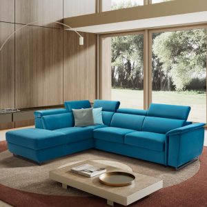 Divano angolare moderno in tessuto blu in soggiorno con grandi finestre e vista sul giardino.