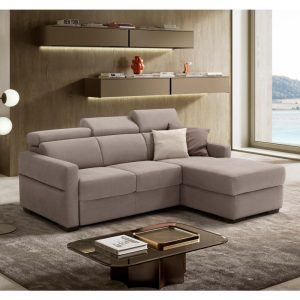 Divano angolare moderno in tessuto beige con cuscini decorativi in un soggiorno elegante e luminoso con vista sul mare.