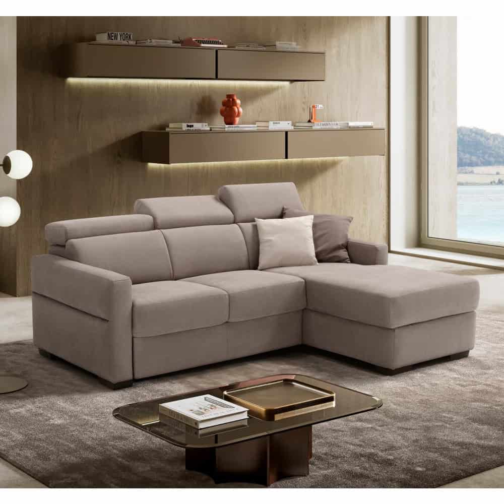 Divano angolare moderno in tessuto beige con cuscini decorativi in un soggiorno elegante e luminoso con vista sul mare.