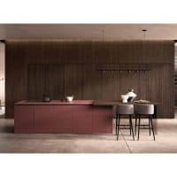 Cucina moderna con mobili in legno scuro e isola centrale in colore rosso mattone, con sgabelli e illuminazione minimalista.