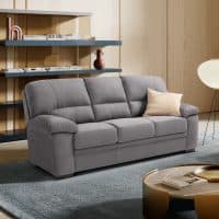 Divano 3 posti ESMI in tessuto grigio con cuscino beige, in soggiorno moderno con scaffali e lampada a terra.