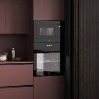 Forno e microonde integrati in cucina moderna con ante colorate in tonalità marrone.