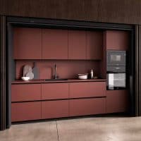 Cucina moderna con ante in finitura opaca color terracotta e elettrodomestici integrati, perfetta per ambienti contemporanei.
