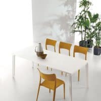 Tavolo EFESTO con sedie gialle in ambiente moderno e luminoso, decorato con vasi e piante verdi, ideale per ambienti eleganti e contemporanei.