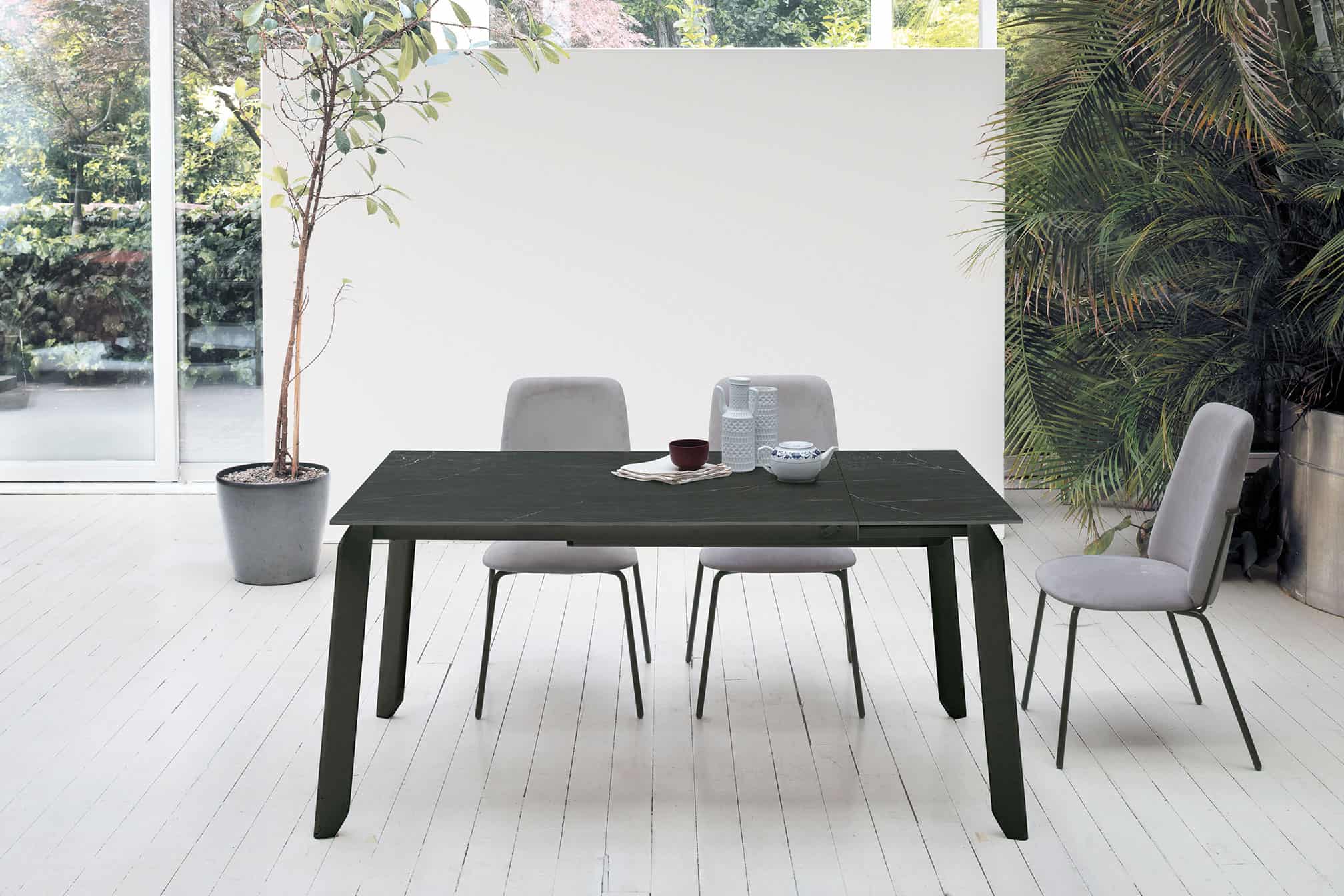 Tavolo EFESTO in legno scuro con sedie grigie in ambiente luminoso e minimalista, ideale per la zona pranzo di casa.