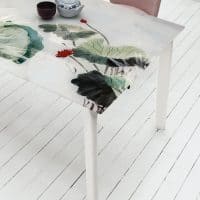 Tavolo EFESTO con superficie decorativa in vetro con stampa botanica, abbinato a sedie rosa, ideale per ambienti moderni e eleganti.