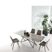 Tavolo moderno Galaxy con piano in marmo e struttura in metallo, accompagnato da sedie imbottite in tessuto, in un ambiente luminoso e minimalista.