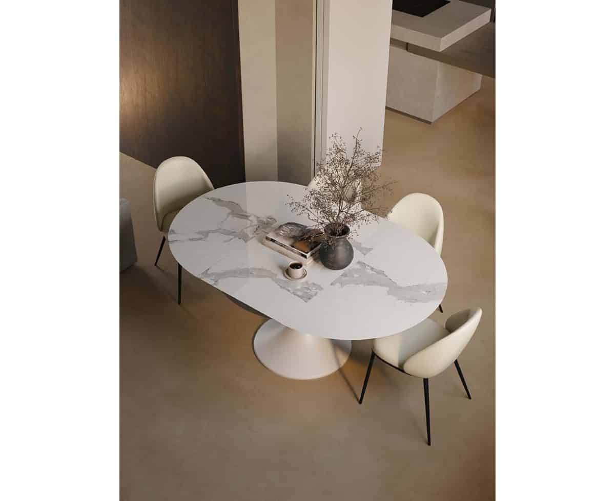 Tavolo allungabile JAZZ con piano in marmo bianco e base rotonda, circondato da quattro sedie moderne in un ambiente elegante e luminoso.