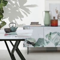 Tavolo KATANA con piano in marmo e gambe nere, ambientato in uno spazio moderno con decorazioni minimaliste e piante verdi.