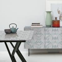 Tavolo KATANA con superficie in legno e struttura nera, ambientato in uno spazio minimalista con decorazioni di design e oggetti d'arte.