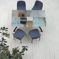 Tavolo KATANA con quattro sedie blu in un ambiente luminoso e minimalista, decorato con piante verdi, ideale per ambienti di design contemporaneo.