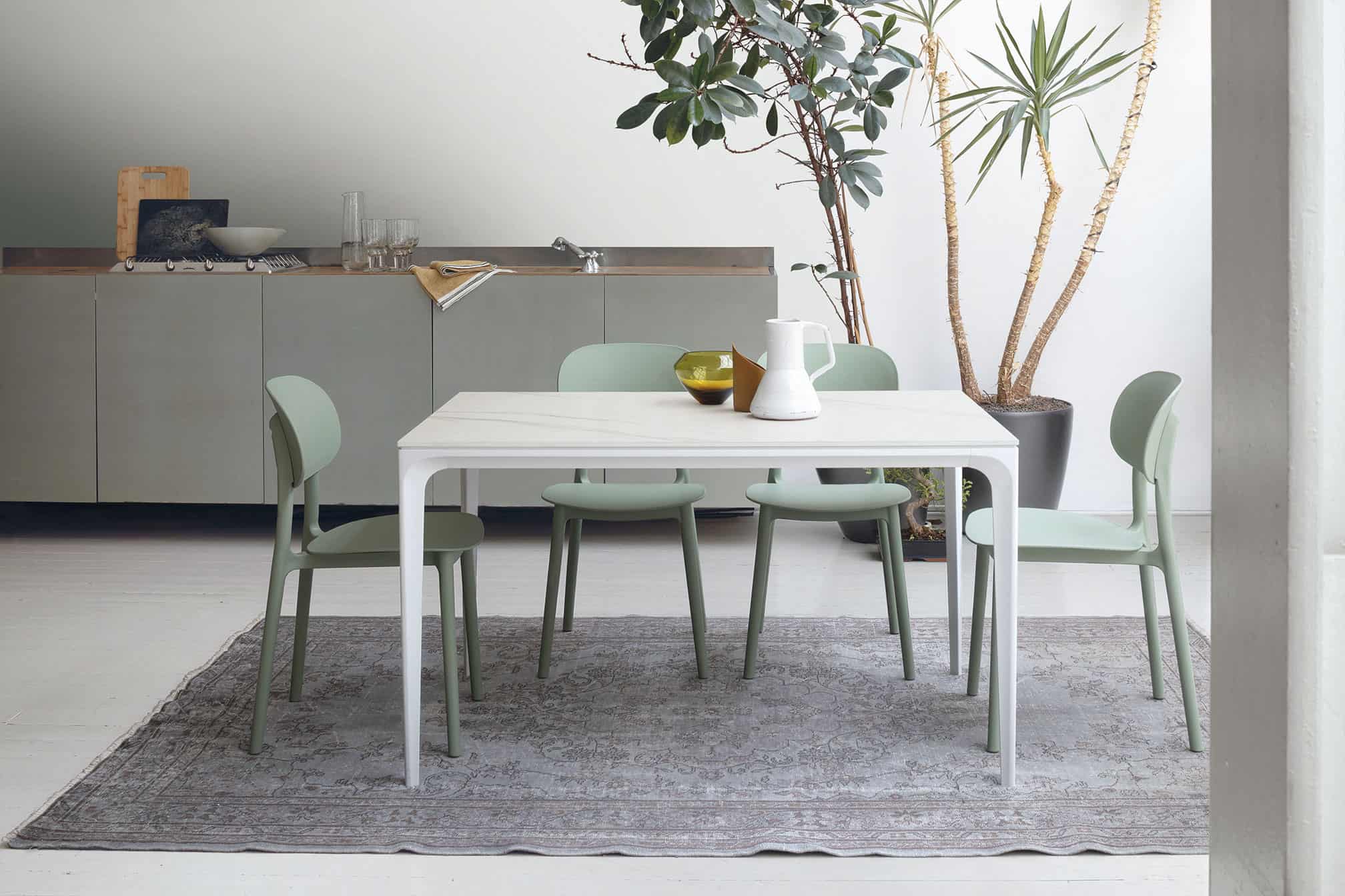 Tavolo moderno Mercury di Alpe Arredi con sedie verdi in un ambiente luminoso e minimalista.
