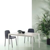 Tavolo moderno Mercury con sedie in tessuto grigio scuro, ambiente minimalista con parete verde e pianta grande.
