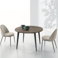 Tavolo rotondo in legno con due sedie imbottite in un ambiente luminoso e minimalista, perfetto per la zona pranzo moderna.
