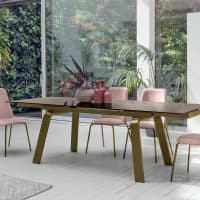 Elegante tavolo MARTE di Alpe Arredi con sedie rosa in un ambiente luminoso e moderno, circondato da piante verdi e grandi finestre che lasciano entrare molta luce naturale.