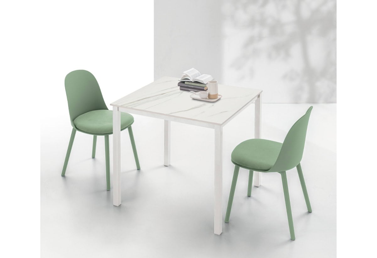 Tavolo PELLICANO con sedie verdi in un ambiente luminoso e minimalista, ideale per ambienti moderni e eleganti.