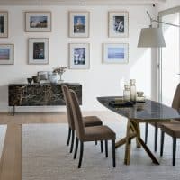 Elegante tavolo in gress con base in legno, ideale per ambienti moderni e raffinati, con sedie imbottite e decorazioni minimaliste.