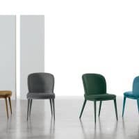 Set di quattro sedie CLEVELAND in diversi colori: beige, grigio, verde e blu, posizionate in un ambiente moderno con pareti bianche e pavimento in cemento.