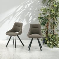 Due sedie Kudo in tessuto marrone con gambe nere in un ambiente minimalista, accanto a una pianta alta.
