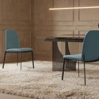 Sedia di colore azzurro posizionata in soggiorno con tavolo moderno e pavimento in legno.