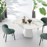 Tavolo TAY con superficie in marmo bianco e sedie verde salvia, ambiente elegante e luminoso con piante verdi sullo sfondo.