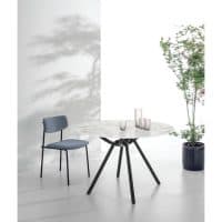 Tavolo moderno con base in legno e piano in marmo, abbinato a sedia in tessuto grigio e pianta decorativa, ideale per ambienti eleganti e contemporanei.